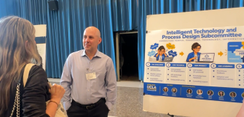 Man talking to a woman near an information poster in a blue curtained room.