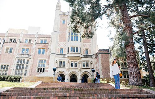 An undergraduate student walks down the steps outside of Kerckhoff Hall