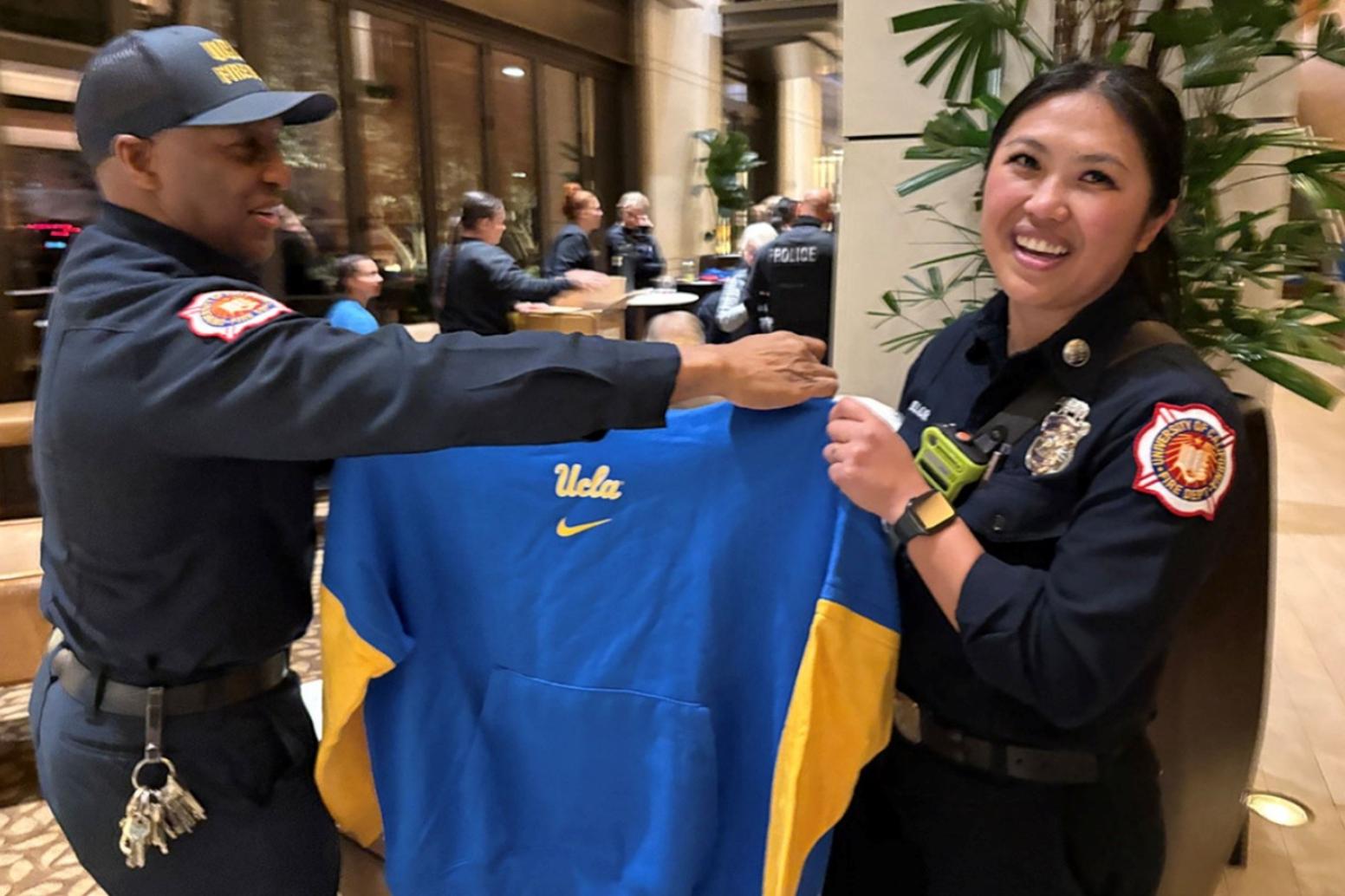 Two members of UCLA Fire holding up a UCLA Softball shirt