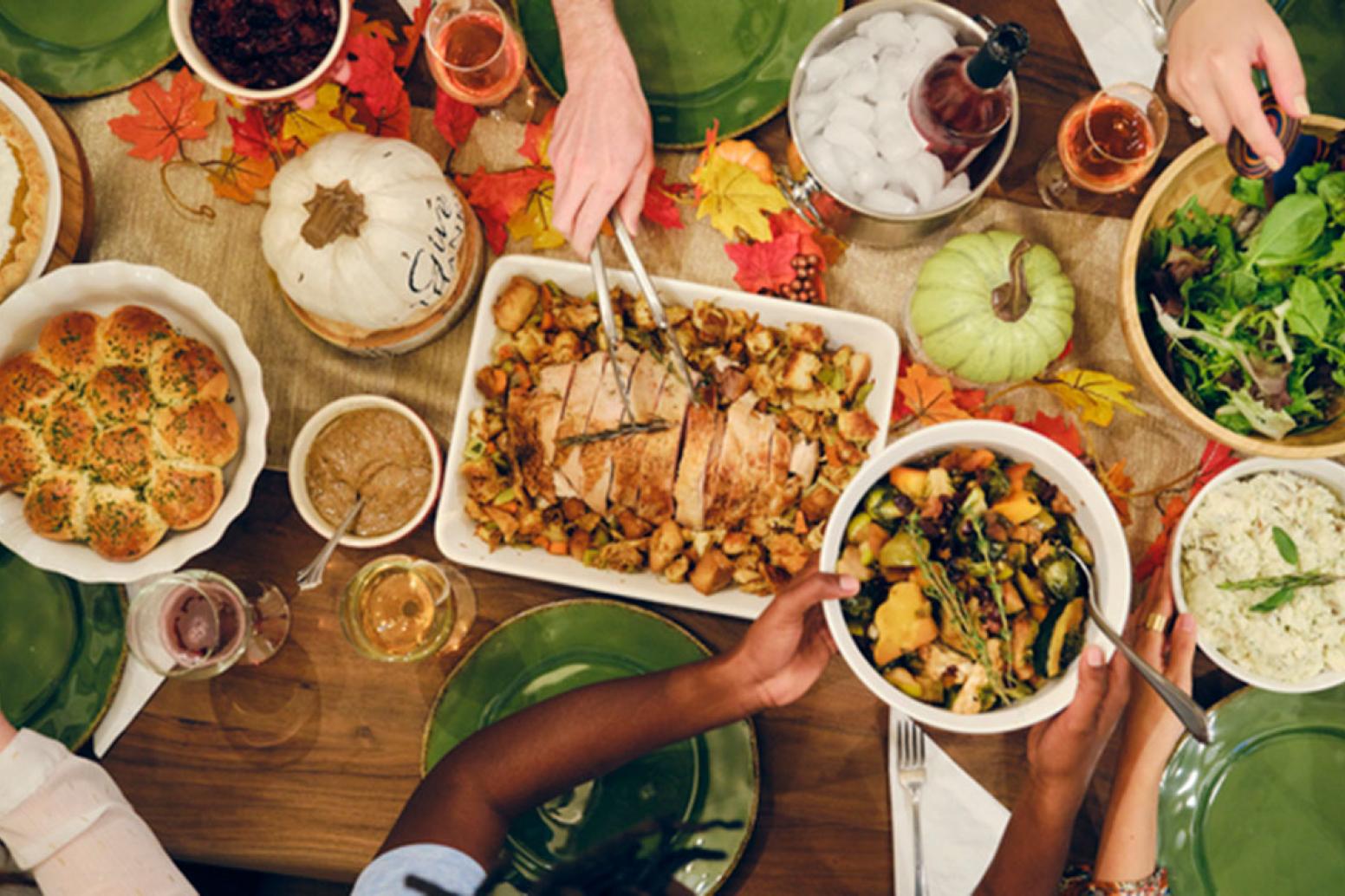 a view of a holiday feast from above including turkey, stuffing, roasted vegetables, salad, dips and bread