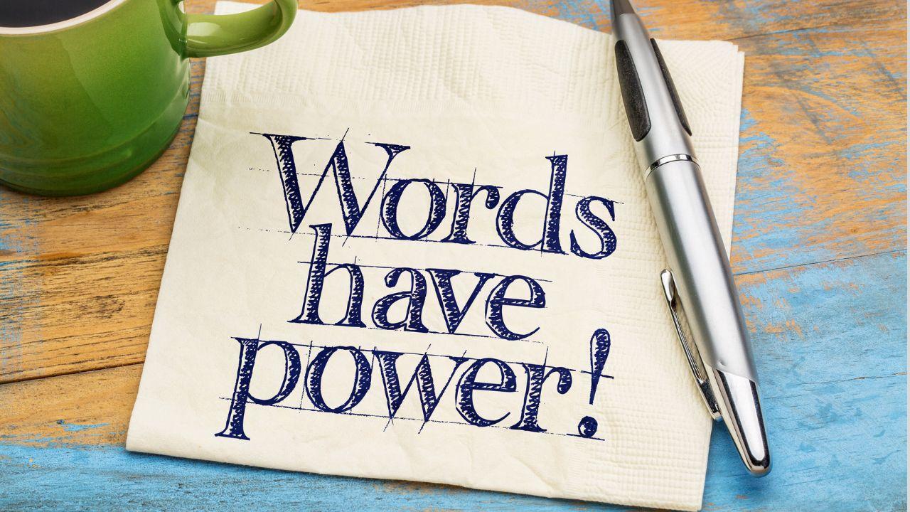 A napkin with the text Words have power! written on it next to a pen and a mug