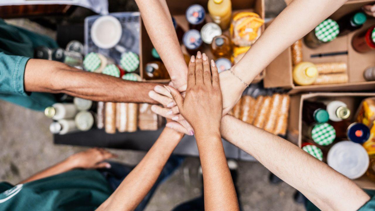 Close-up of volunteers with hands stacked during donation event.