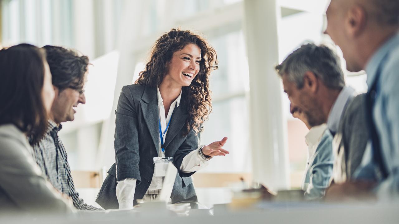 Happy female leader talking to her colleagues during a business meeting in the office.