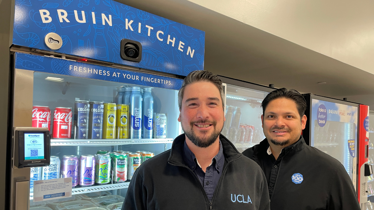 Two men in front of the grab and go at Bruin Kitchen