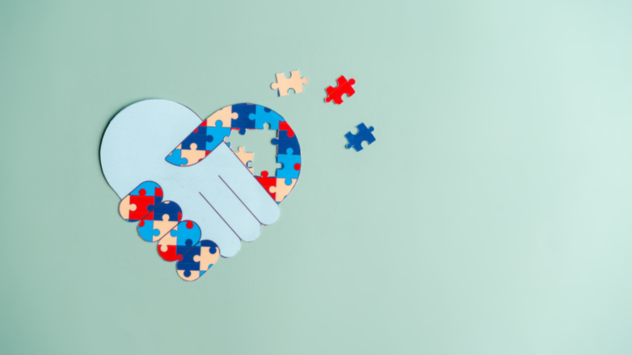 Puzzle pieces forming a heart-shaped handshake