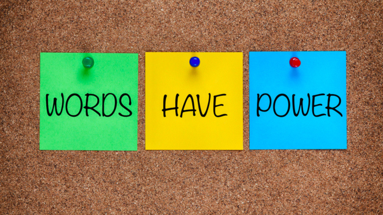 A group of colorful notes pinned to a cork board which spell Words Have Power.