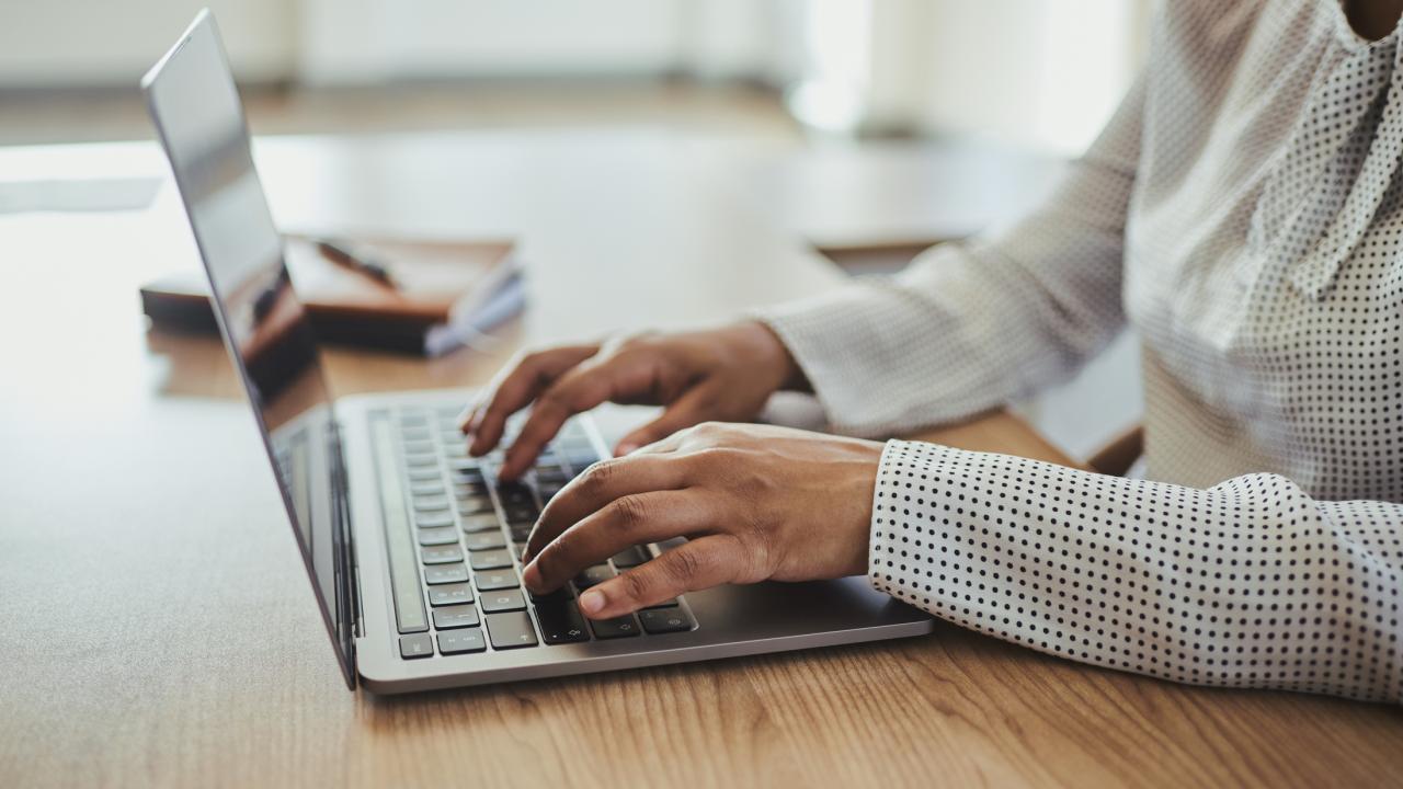 Two hands typing on a laptop keyboard