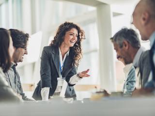 Happy female leader talking to her colleagues during a business meeting in the office.